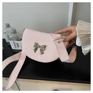 Détail du sac selle rose à texture marbrée avec nœud argenté et large bandoulière