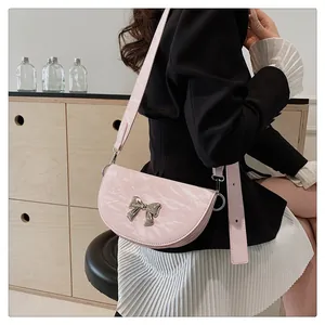 Vue détaillée du sac selle rose clair avec nœud argenté porté par un mannequin