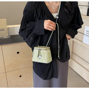 Détail d'un mini sac seau vert menthe avec texture gaufrée et bandoulière chaîne argent