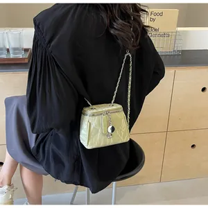 Détail du sac seau en cuir plissé vert clair avec bandoulière en chaîne argentée