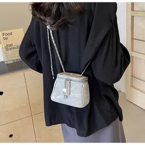 Détail d'un mini sac vanity argenté plissé avec bandoulière chaîne porté par un mannequin