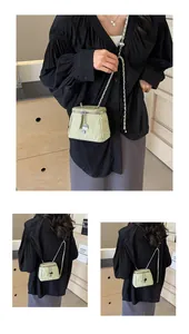 Détail du mini sac seau plissé vert clair avec chaîne argentée et pendentif en métal
