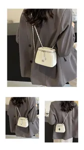 Détail du sac seau matelassé crème avec bandoulière chaîne argentée et breloque fleur