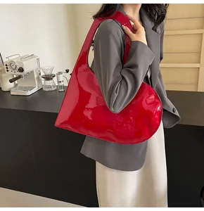 Detailed view of glossy red patent leather shoulder bag with a unique curved silhouette