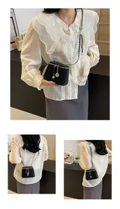 Détail du mini sac seau noir matelassé avec bandoulière chaîne et pendentif fleur