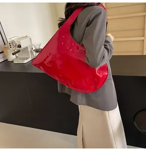 Detailed view of the large red glossy patent leather shoulder bag carried by a model