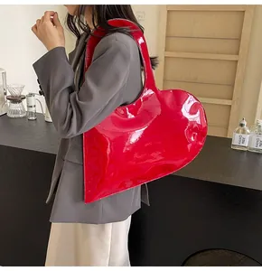 Detail of red patent leather heart-shaped shoulder bag with glossy finish and large capacity