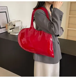 Detail of red glossy patent leather handbag showing the unique heart shape and mirror finish