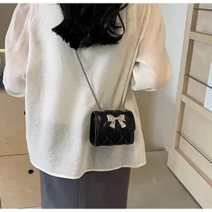 Détail du mini sac matelassé noir avec nœud en métal argenté et bandoulière chaîne