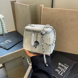 Mini sac seau matelassé blanc avec chaîne argentée et boule réglable sur fond minimaliste
