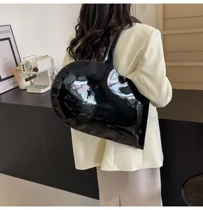 Detail of a large heart-shaped shoulder bag in black patent leather with mirror finish