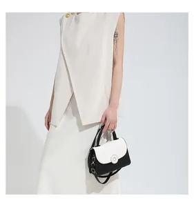 Détail d'un sac bandoulière noir et blanc doté d'une fermeture magnétique ronde
