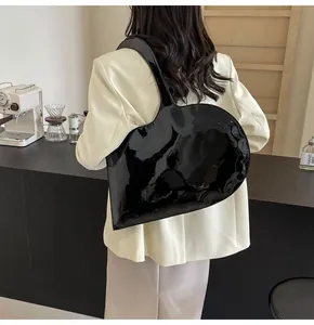 Detail of glossy black heart-shaped shoulder bag featuring a modern asymmetrical design