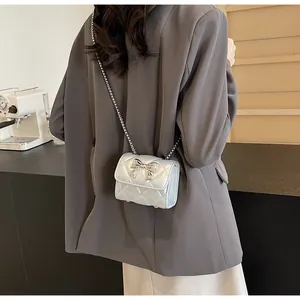 Sac bandoulière argenté matelassé avec nœud papillon porté à l'épaule