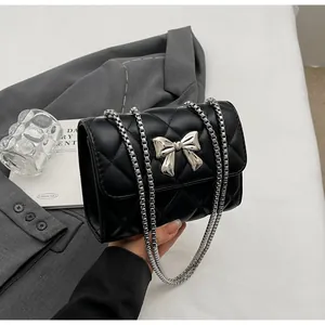 Détail du sac à bandoulière matelassé noir avec nœud métallique argenté et double chaîne