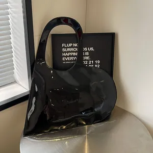 Glossy black heart-shaped handbag with unique round handle and sleek geometric silhouette
