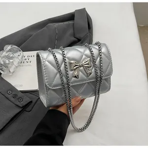Détail du sac bandoulière argenté matelassé avec fermoir nœud et chaîne en métal