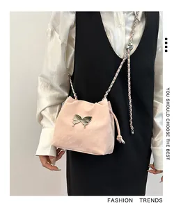 Détail du sac seau rose avec breloque papillon argentée et bandoulière chaîne en métal