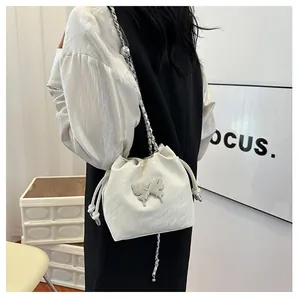 Détail du sac seau blanc crème avec papillon argenté et bandoulière chaîne sur mannequin