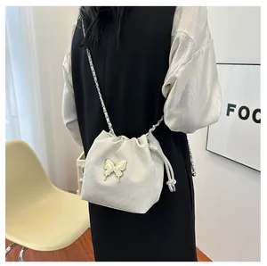 Détail du sac seau crème avec papillon argenté et bandoulière en chaîne métal
