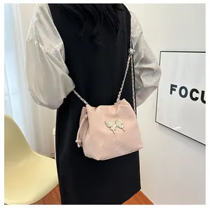 Détail du sac seau rose avec ornement papillon argenté et bandoulière en chaîne
