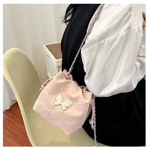 Détail du sac seau rose clair avec décoration papillon et bandoulière chaîne sur modèle
