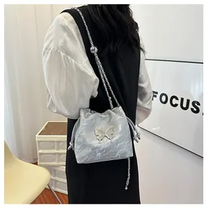 Détail du sac seau argenté métallisé avec chaîne papillon et fini texturé sur mannequin