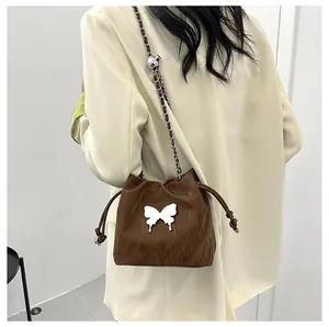 Détail du sac seau marron foncé avec décor papillon blanc et bandoulière en chaîne