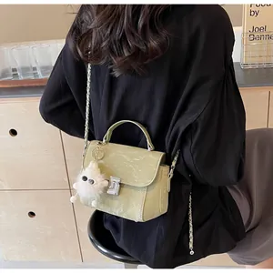 Détail du sac bandoulière vert avocat avec surpiqûres losanges et breloque boule en peluche