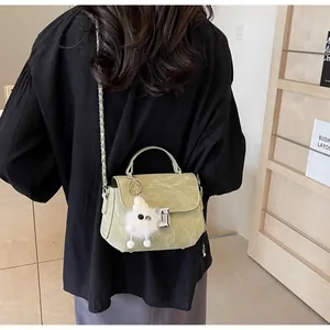 Détail d'un sac à main matelassé vert sauge avec charme en peluche et boucle dorée