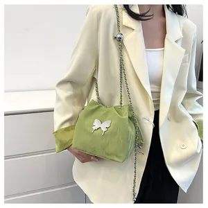Détail d'un sac seau vert avec breloque papillon argentée et bandoulière chaîne