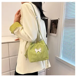 Détail du sac seau vert clair avec papillon argenté et bandoulière chaîne sur modèle