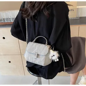 Détail d'un sac à main gris matelassé avec fermoir argenté et breloque en peluche