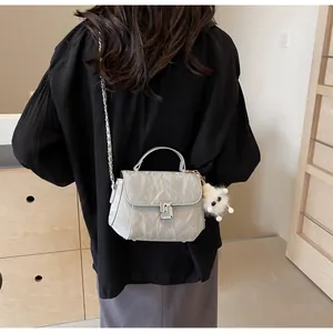 Sac bandoulière matelassé argenté avec fermoir métal et charm peluche porté par mannequin