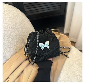 Détail du sac seau noir à cordon avec breloque papillon argentée et bandoulière