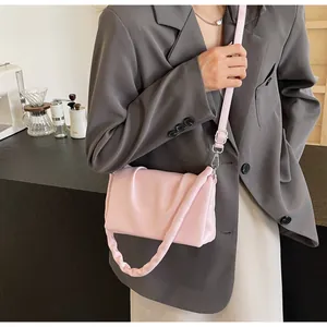 Vue détaillée du sac bandoulière rose plissé porté avec un blazer gris chic