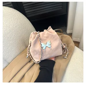 Détail macro du sac seau rose avec boucle papillon argentée et bandoulière en chaîne