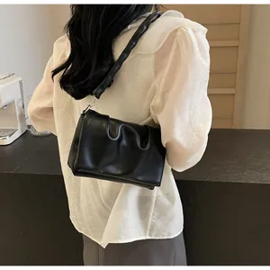 Détail du sac à bandoulière froncé noir avec texture brillante et anneaux argentés