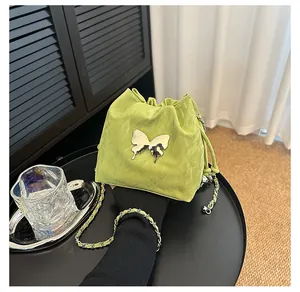 Détail du sac seau vert clair à cordon avec ornement papillon en métal argenté