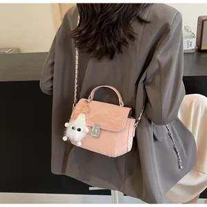 Détail du sac à bandoulière rose clair avec texture matelassée, fermoir et porte-clés