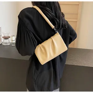 Détail du sac bandoulière plissé beige avec texture en cuir souple sur un mannequin