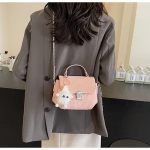 Sac bandoulière matelassé rose avec breloque peluche et chaîne argentée sur modèle