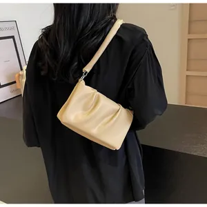 Détail d'un sac à bandoulière plissé beige crème en cuir souple avec anneaux argentés