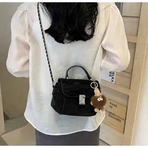 Vue détaillée du sac bandoulière en cuir verni noir avec fermoir argenté et petit pendentif