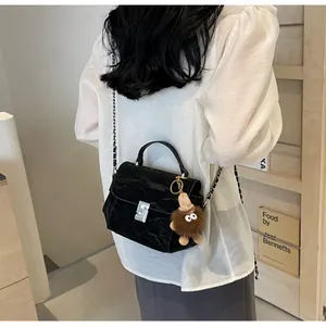 Détail d'un sac à main noir matelassé brillant avec fermoir argenté et breloque peluche