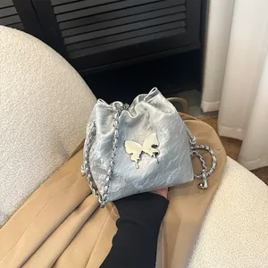 Sac seau argenté métallisé avec papillon et bandoulière chaîne sur tissu neutre