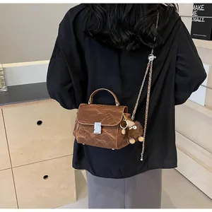 Vue arrière d'un sac à main en cuir marron matelassé avec pendentif monstre en peluche