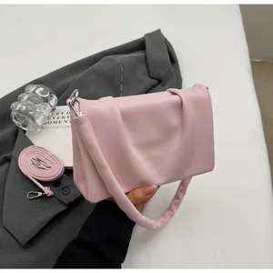 Détail du sac à main plissé rose sur blazer gris avec bandoulière réglable incluse