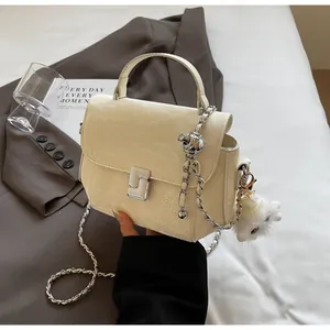 Détail du sac à main plissé blanc cassé avec base matelassée et breloque ours en peluche