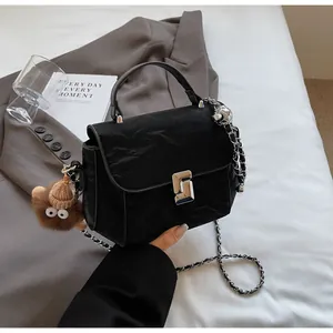 Détail du sac à main noir matelassé avec chaîne argentée et pendentif monstre en peluche